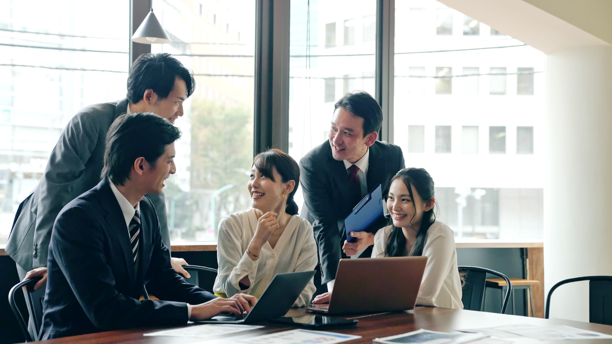 パソコンを見て話し合う５人の会社員