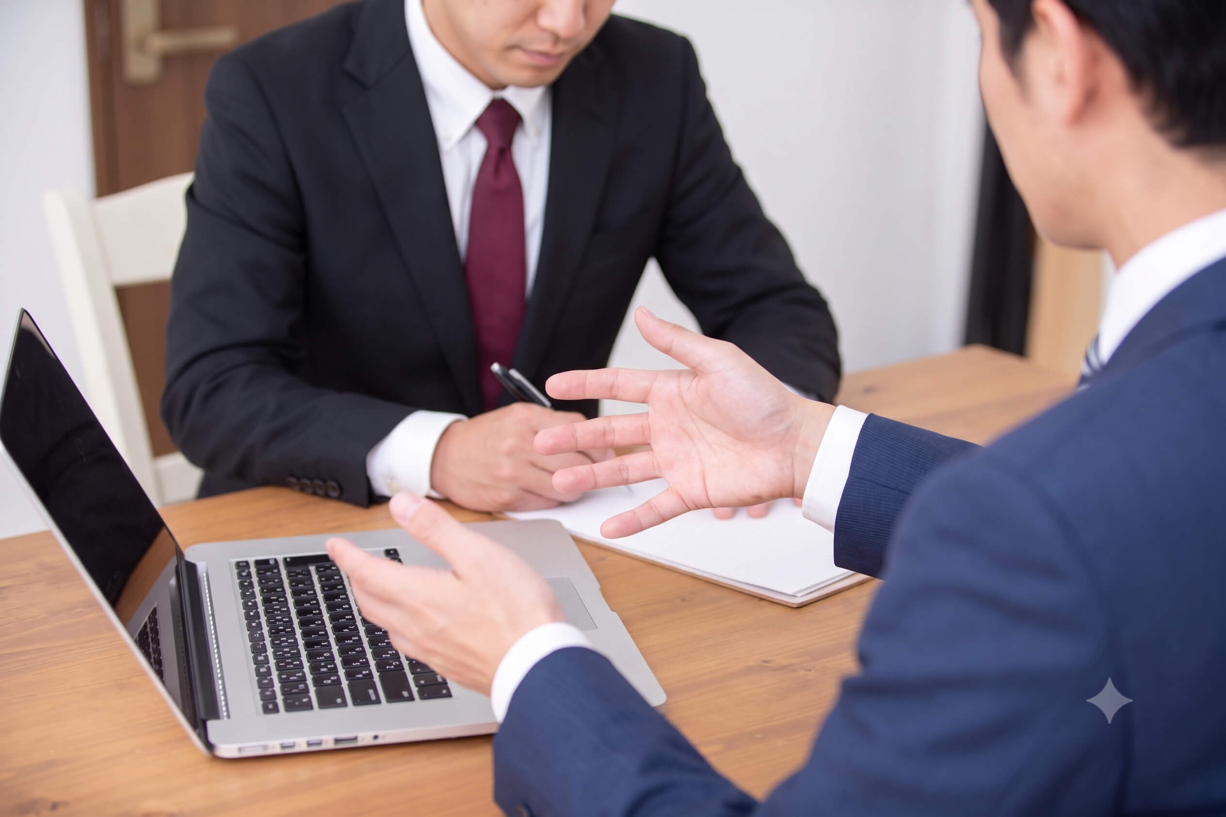木製デスクで商談をする二人の男性